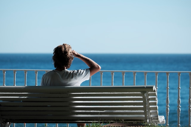 person sitting on bench looking at horizon